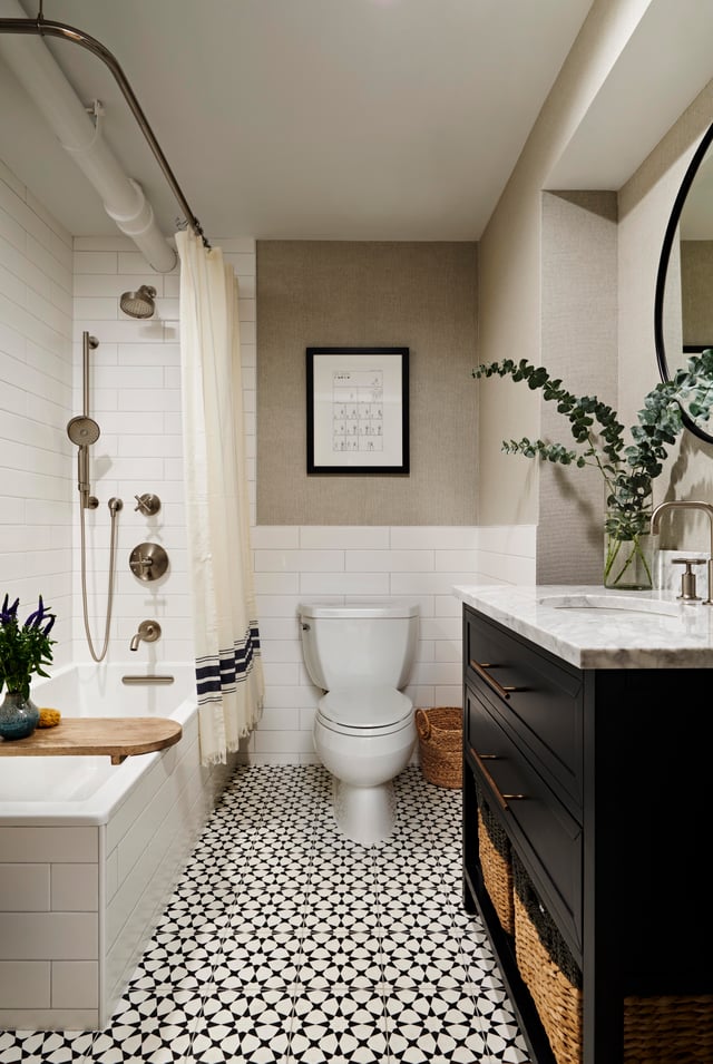  Elegant bath with black vanity and patterned tile floors.