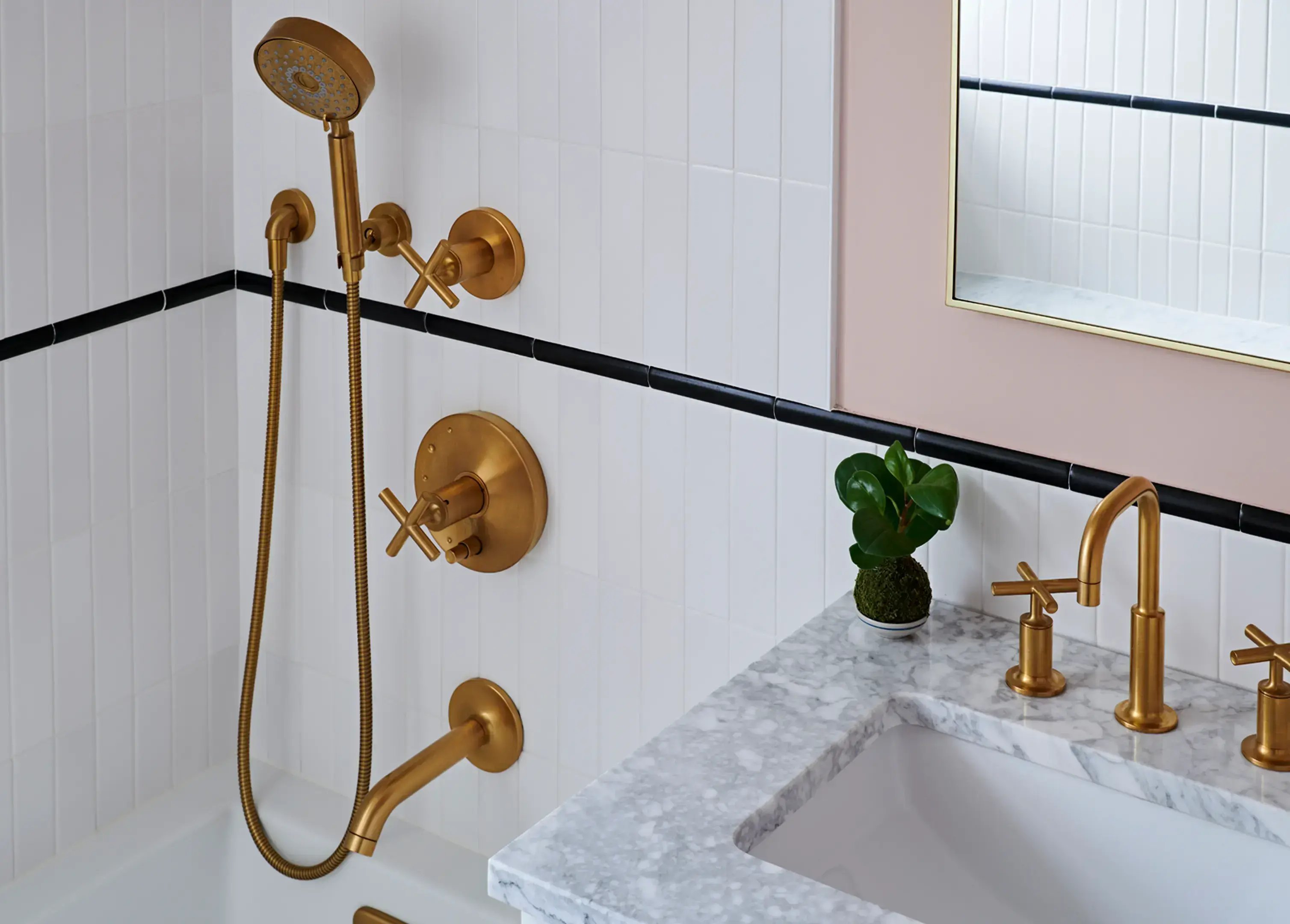 Gold bathroom fixtures, marble vanity, and white tiles.