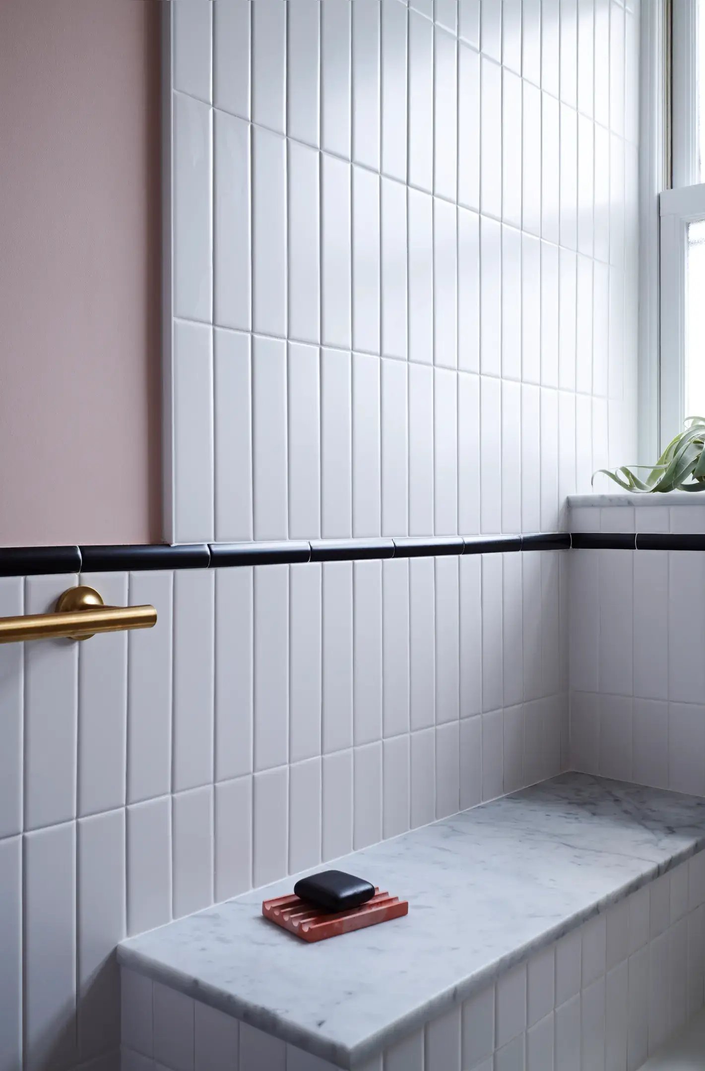 White vertical tiles, a marble bench, and a gold bar.