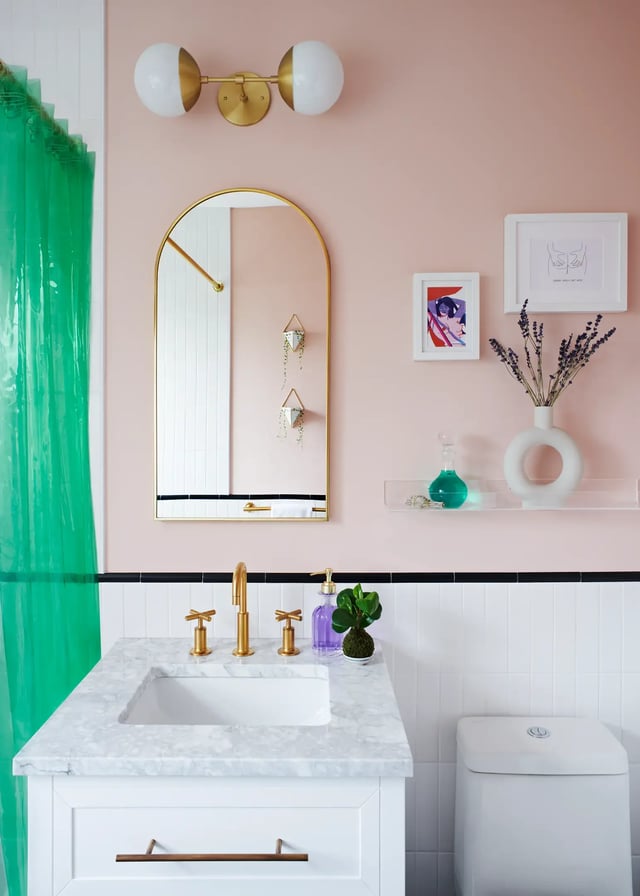 Pink bathroom vanity with gold fixtures and green curtain.