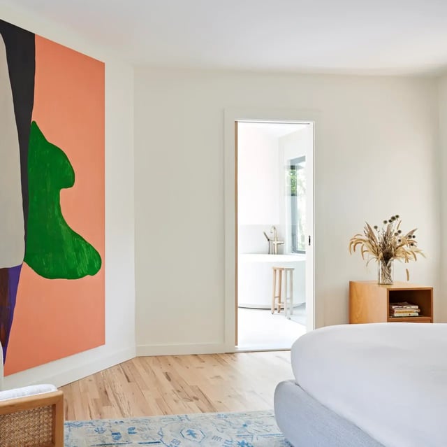 Bright bedroom with abstract art and a bathroom view.