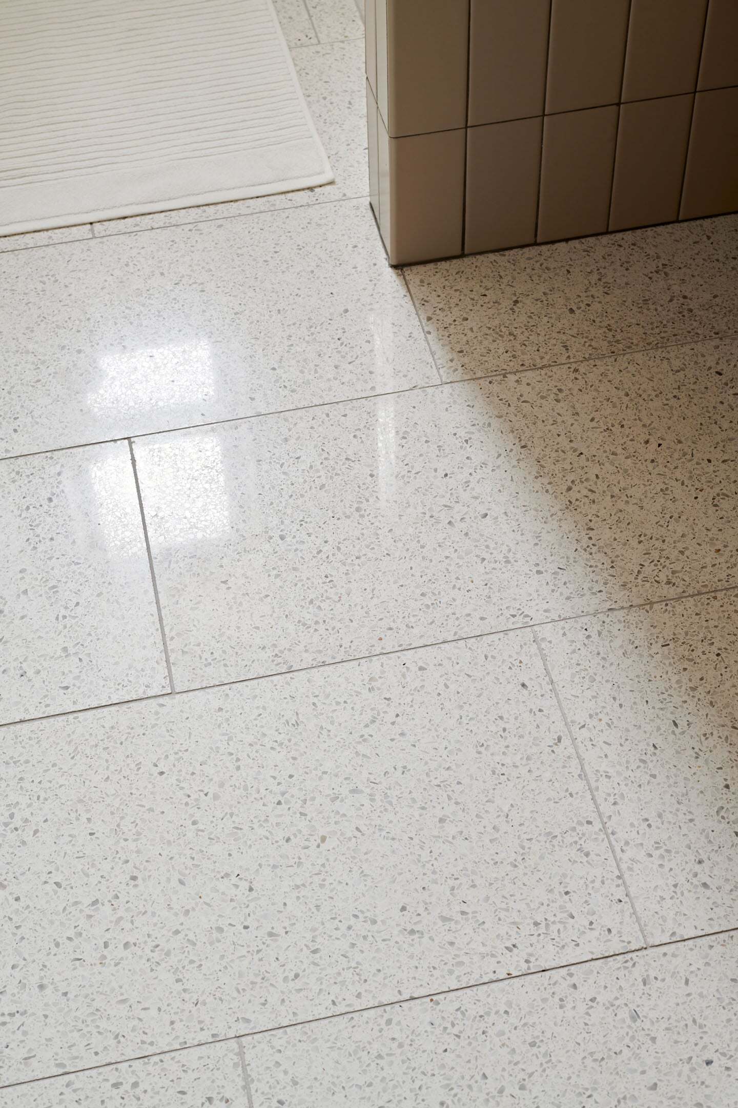 Polished terrazzo bathroom floor with soft shadows and rug