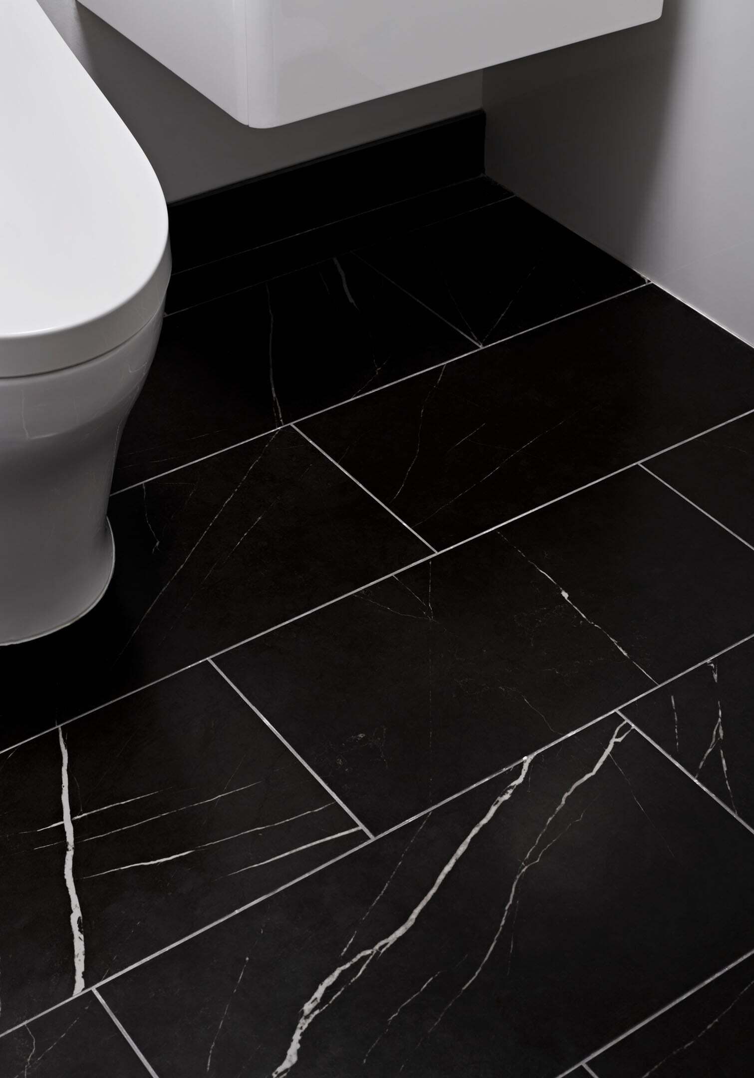 Black marble bathroom floor tile with white veining and toilet