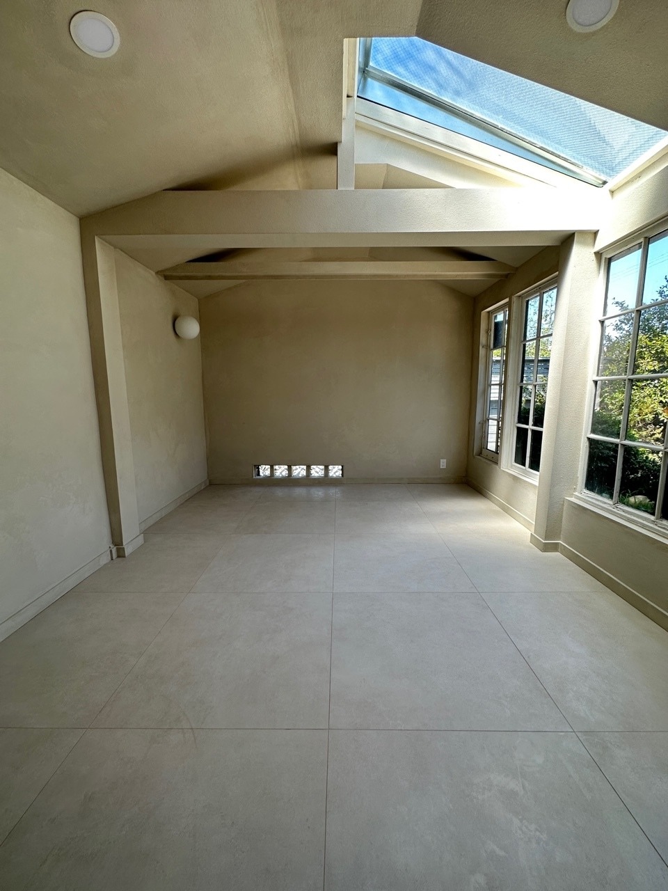 Sunroom with beige walls, tile flooring, and a skylight.