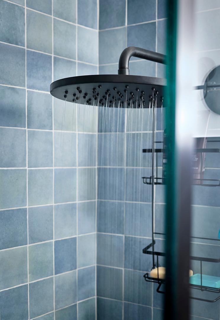 Blue tiled shower with a running black rain showerhead.