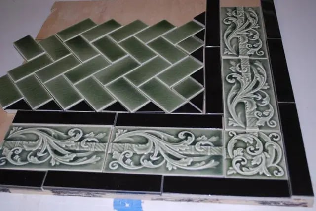 Green herringbone tiles with black and ornate borders.