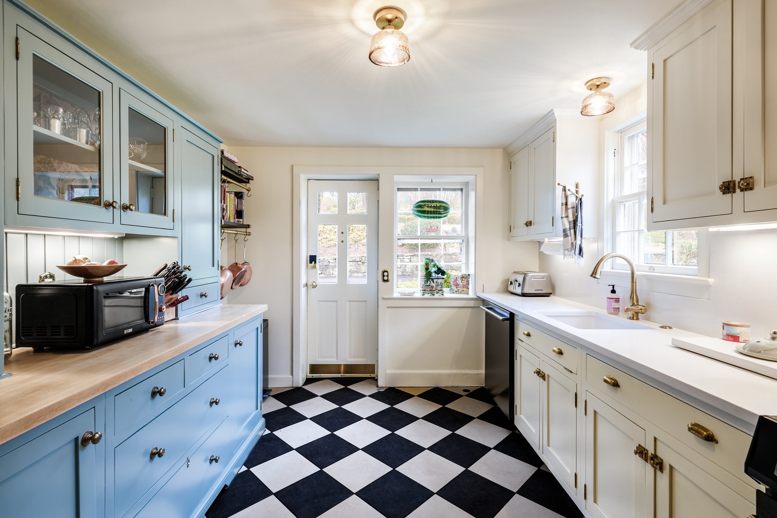 Kitchen with blue and white cabinets and checkered floor.