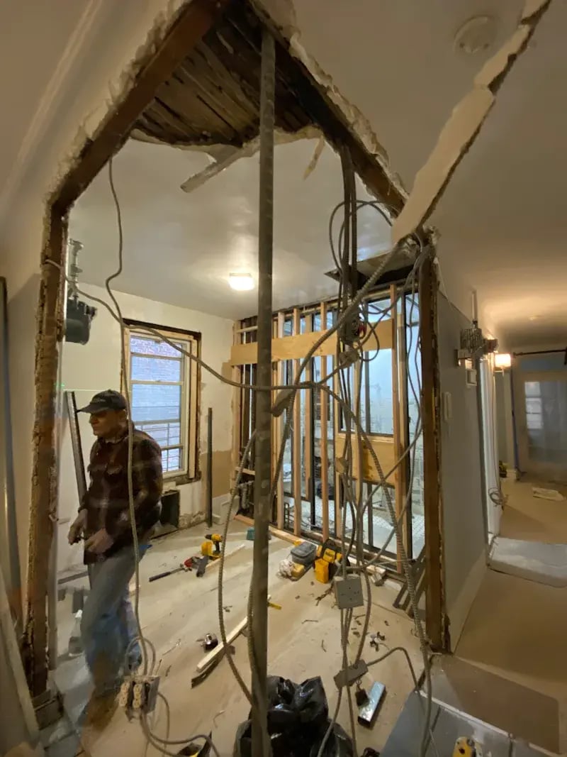 Home renovation scene with exposed wires and a worker.