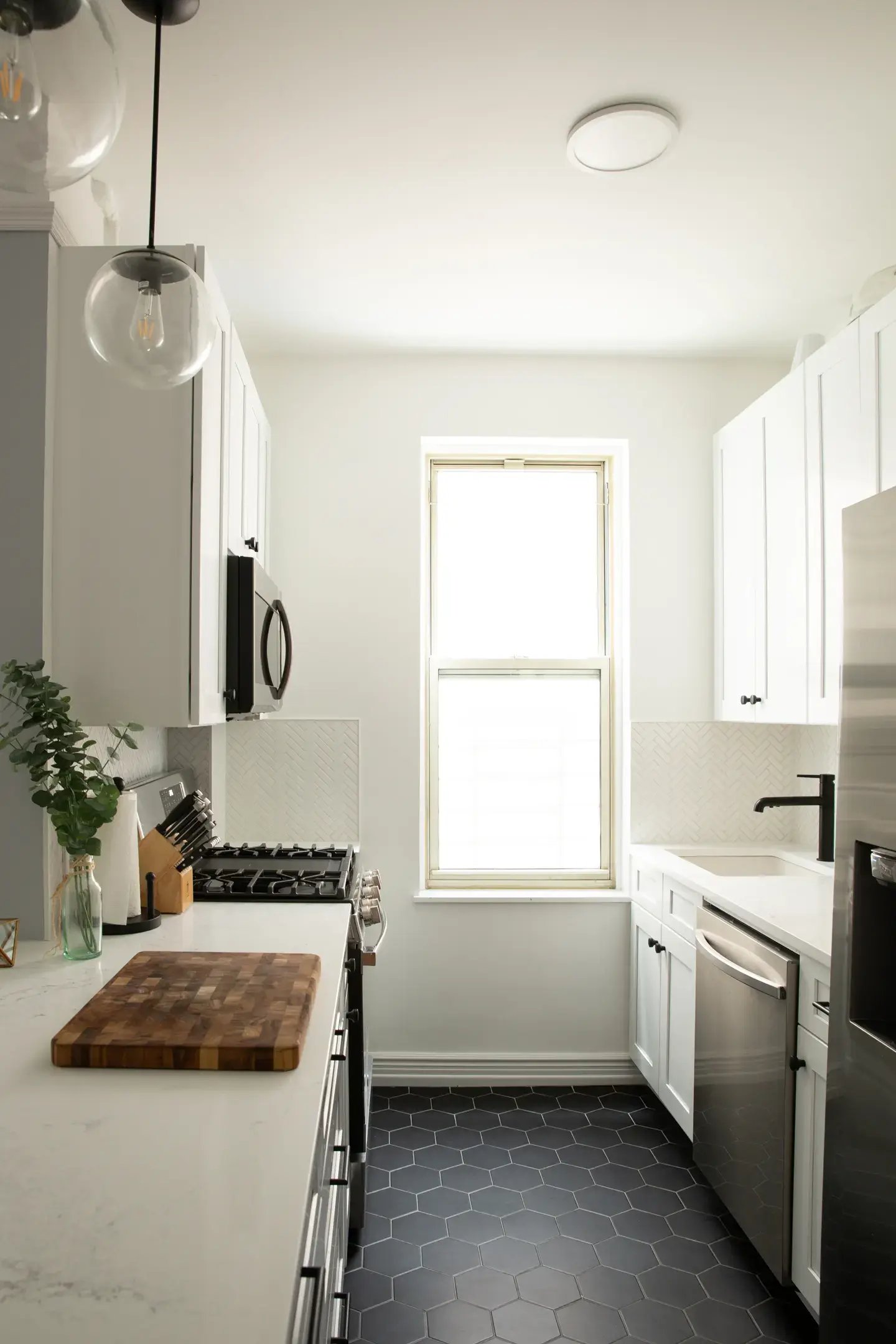 Galley kitchen with white cabinets and black hexagon floor.