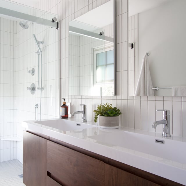 Modern bathroom with double sink vanity and white tiles.