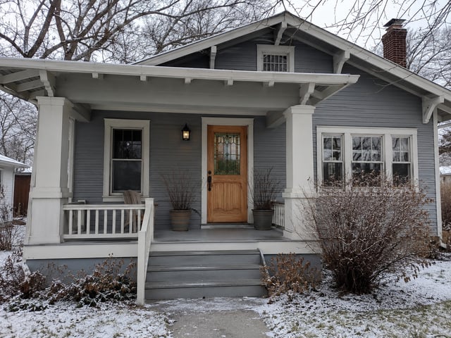 Grey craftsman bungalow with a front porch and wood door.