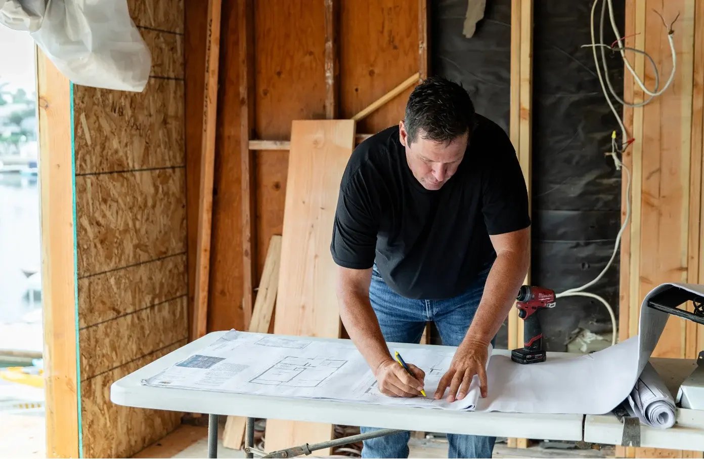 A man reviewing construction blueprints inside a garage.