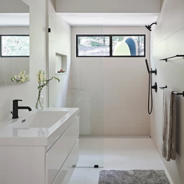 Modern minimalist white bathroom with glass shower and black fixtures