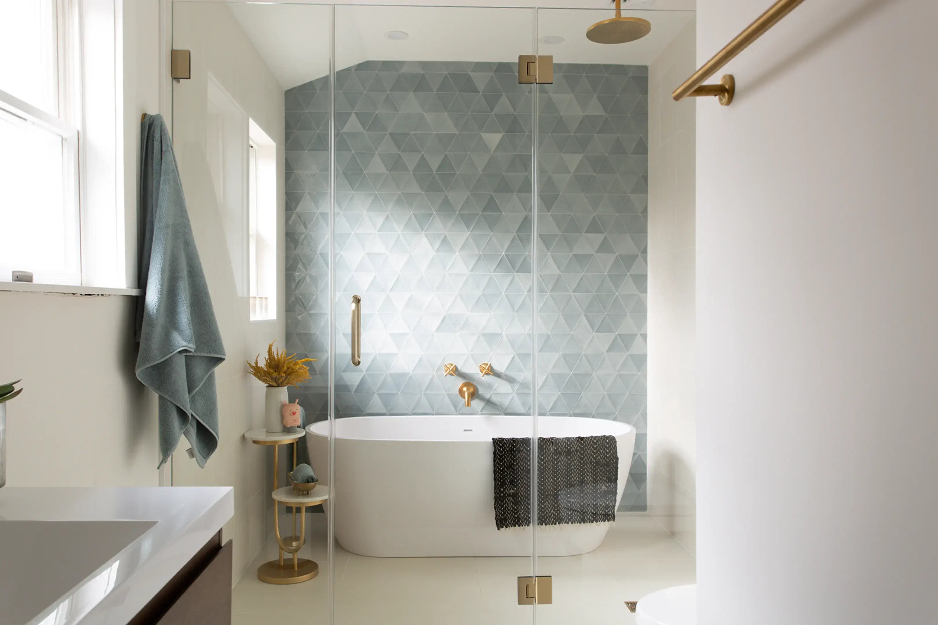 Modern bath with blue triangle tiles and brass hardware.