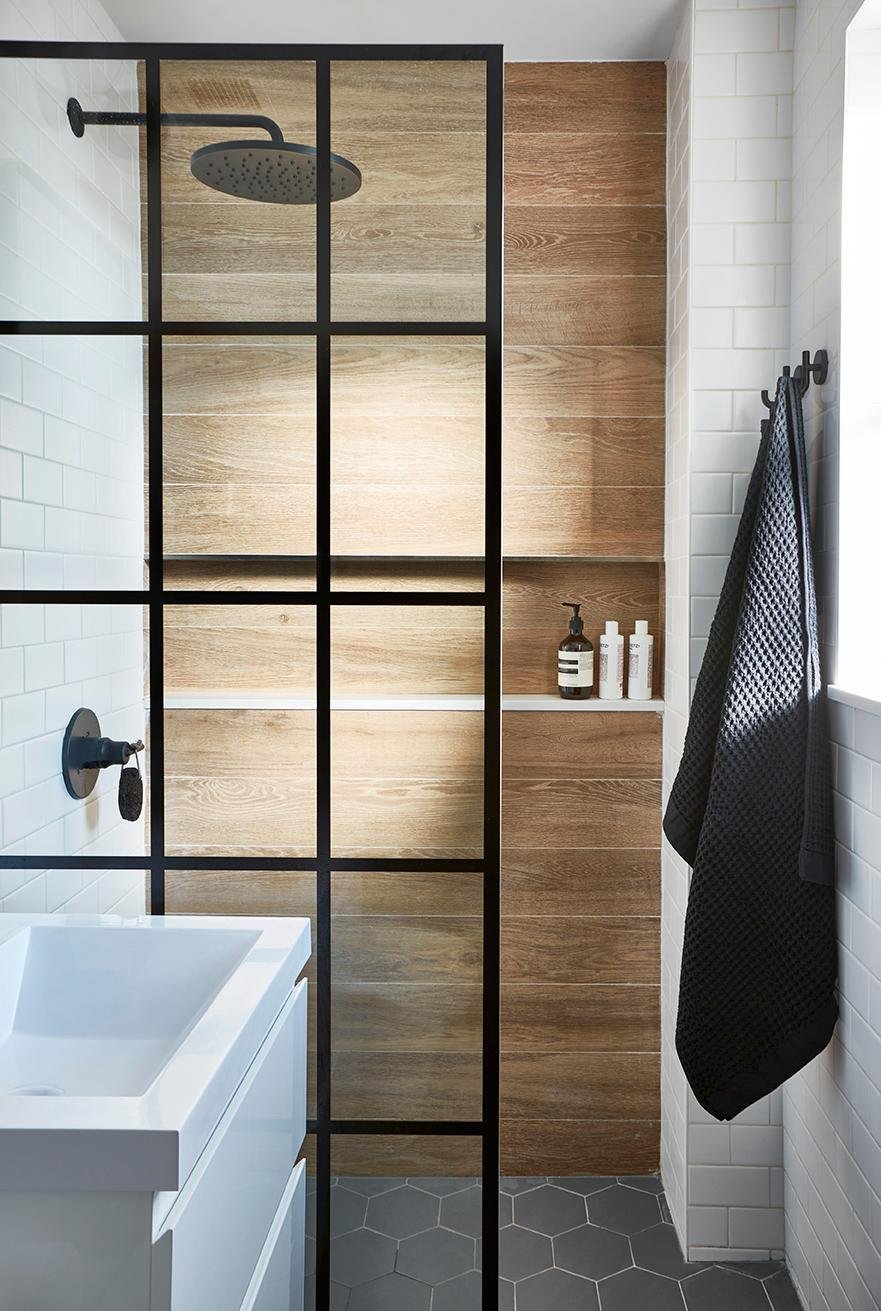 Modern bathroom with wood tile, glass screen, and rain head.