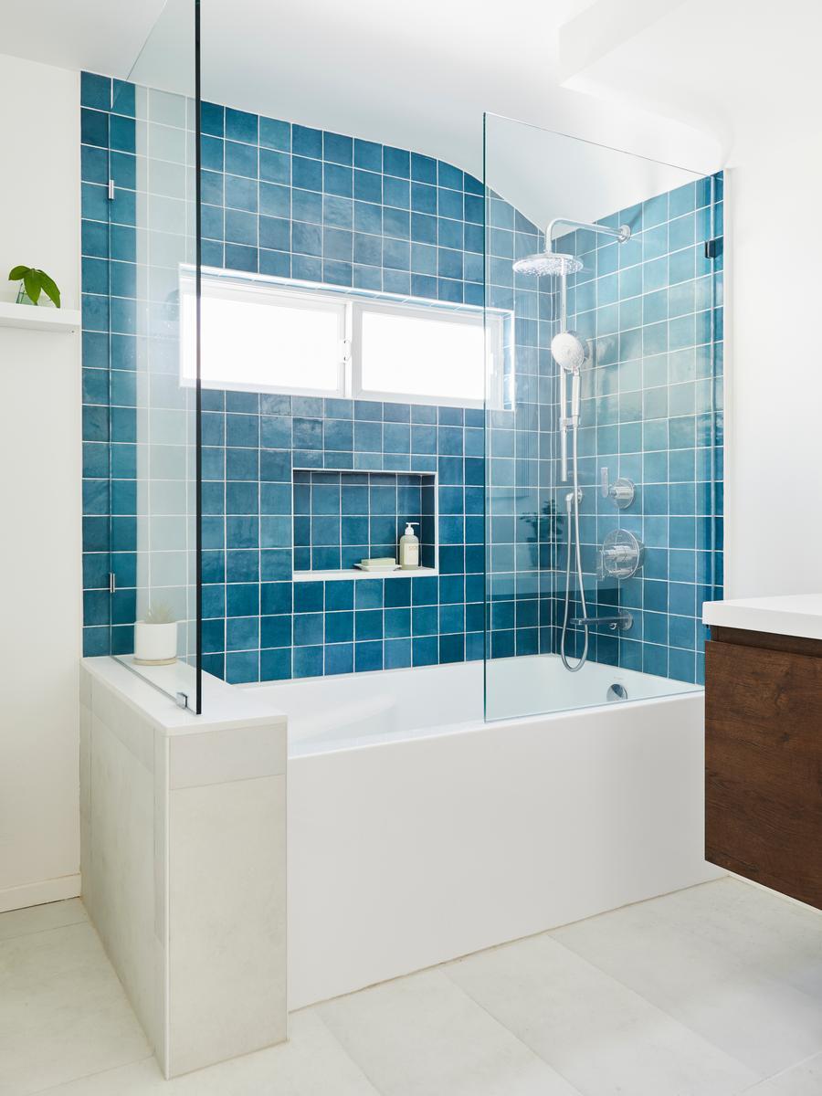 Blue tiled tub and shower combo with frameless glass doors.