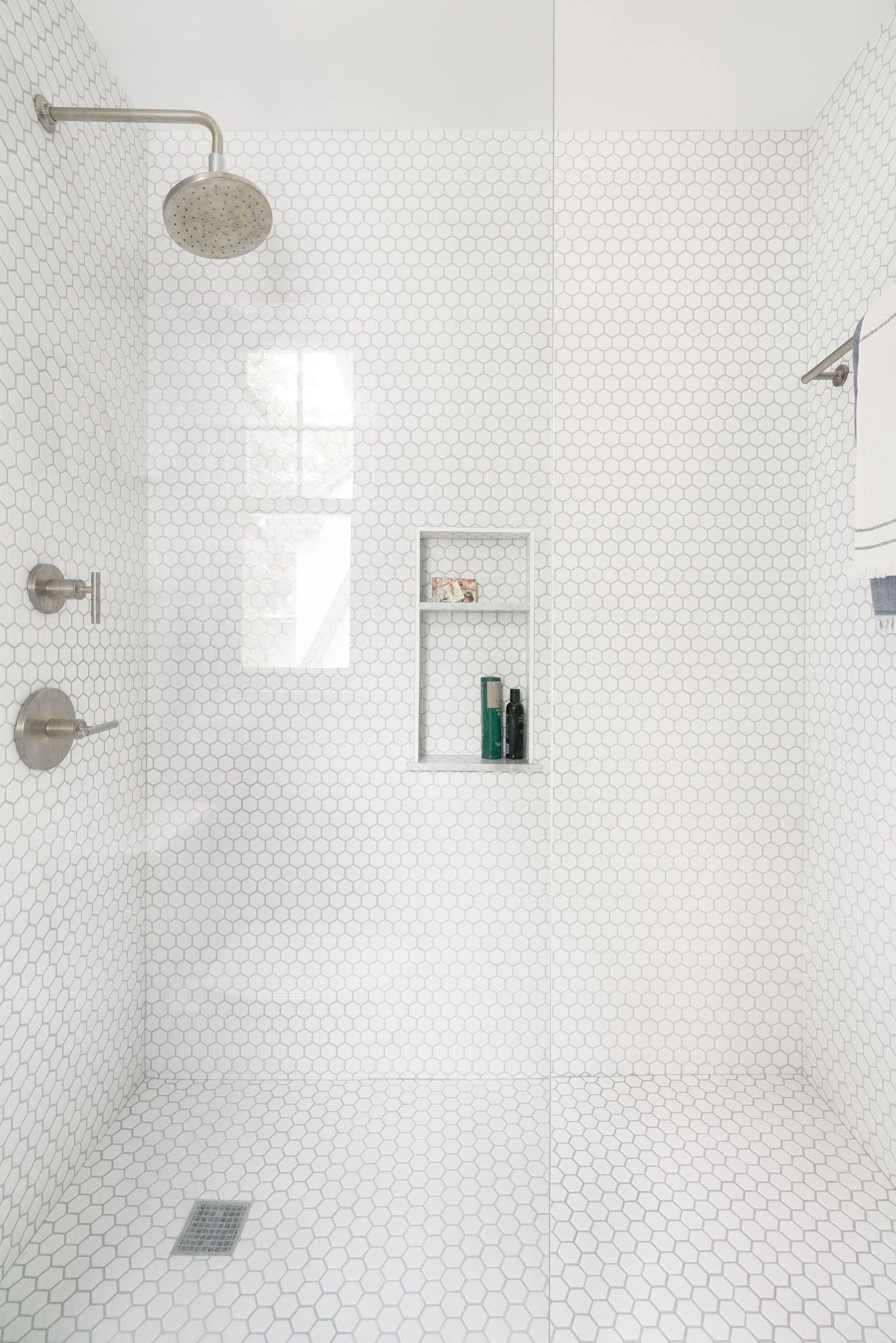 White hex tile shower with glass panel and nickel fixtures.