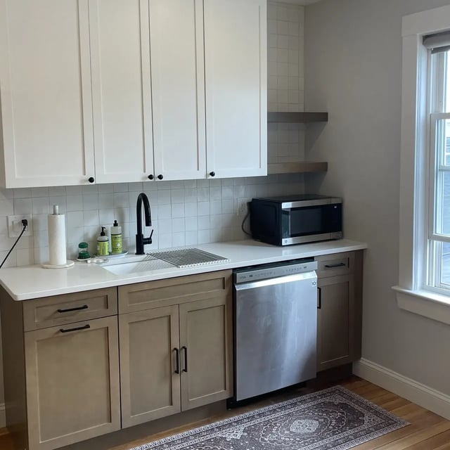 Kitchen with white and brown cabinets, plus a microwave.