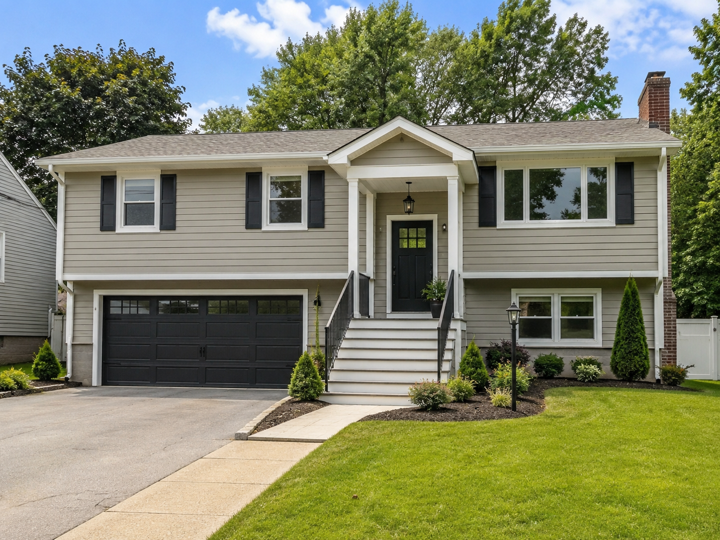 Gray raised ranch house with a black garage door.