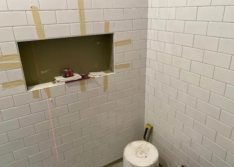 White subway tile installation in shower with a niche.