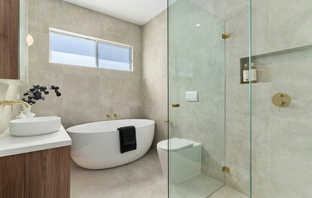 Modern bathroom with beige stone tiles and a freestanding tub.