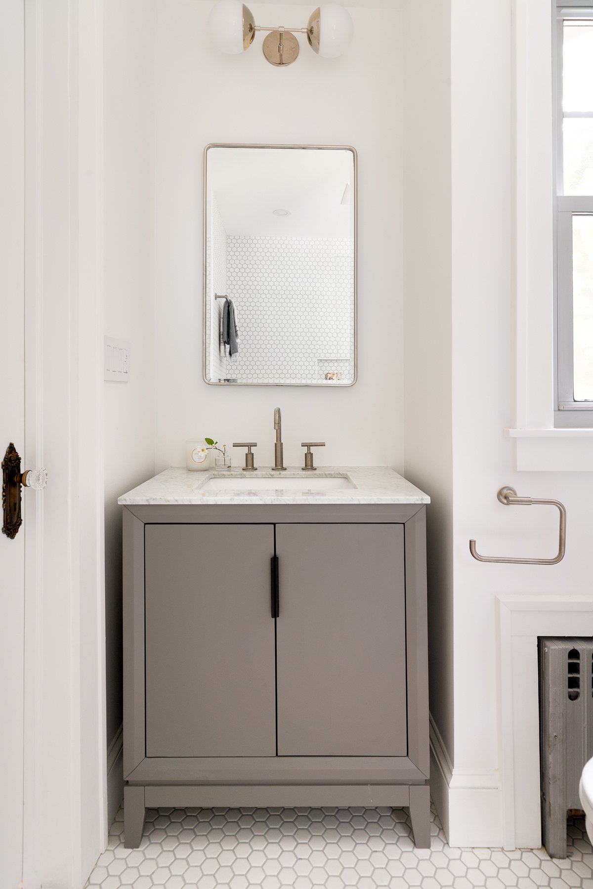 White bathroom with a grey vanity and rectangular mirror.