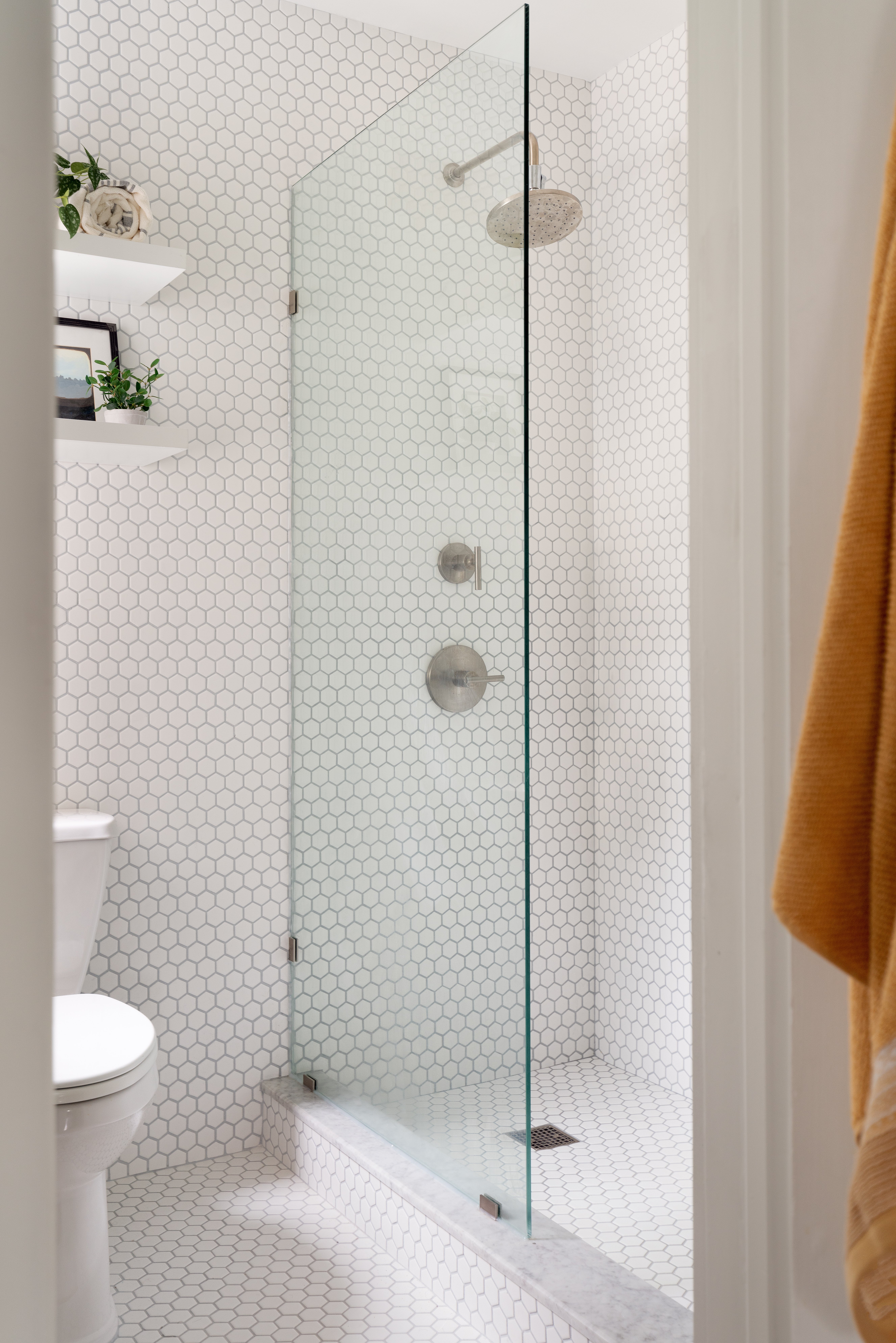 Modern bathroom with white hexagon tiles and a glass shower.