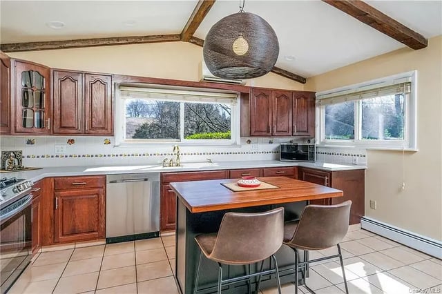 A kitchen featuring wood cabinets, tile flooring, and a central island with two chairs.