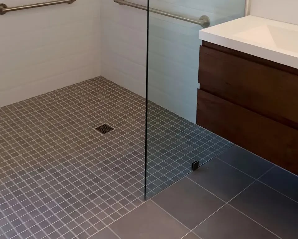 Accessible bathroom with curbless shower and wood vanity.