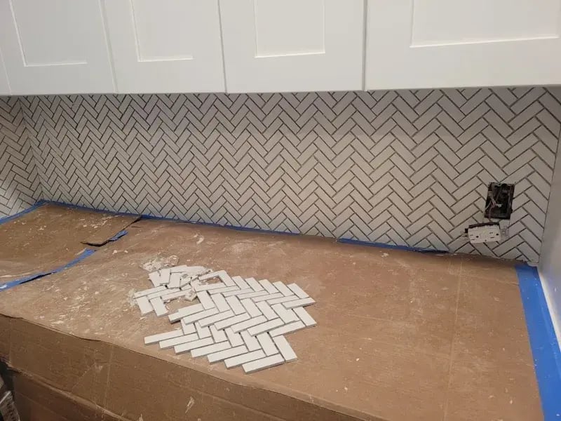 White herringbone tile backsplash under kitchen cabinets.