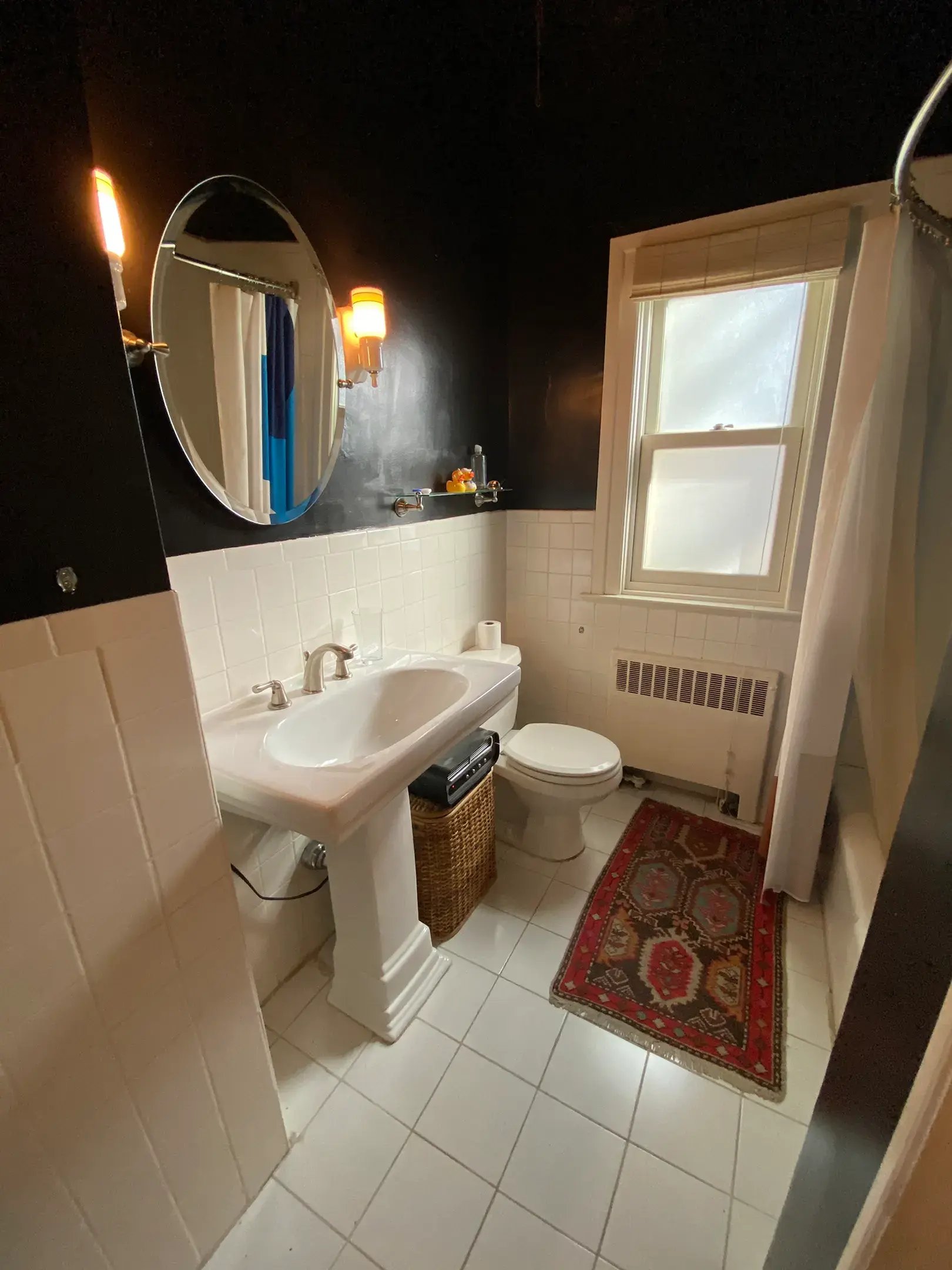 Bathroom with black walls, white tiles, a pedestal sink.