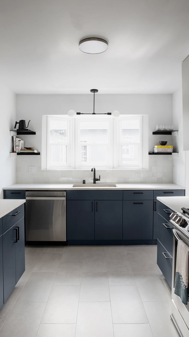 Los Angeles kitchen remodel with blue slab cabinets, white countertops, gray tile floors, and matte black fixtures