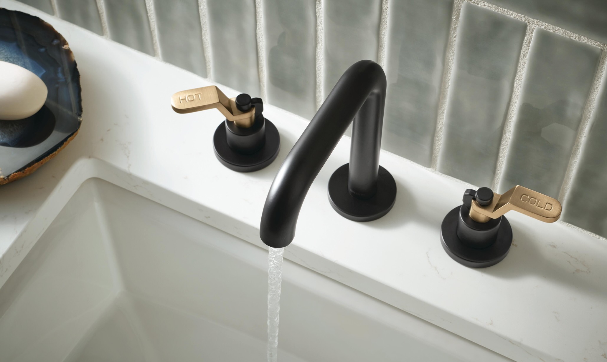 Black and brass bathroom faucet over a white sink.1