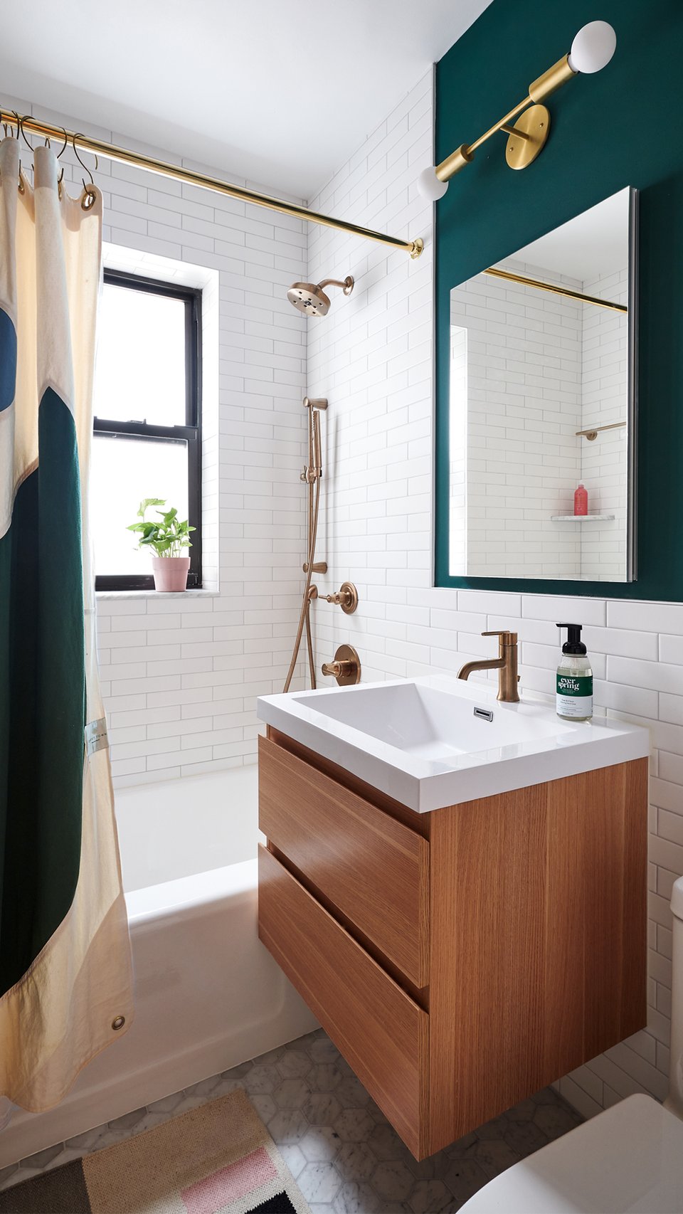 New York bathroom with green walls, white subway tile, brass fixtures, and a wood vanity