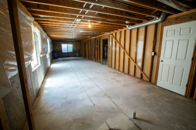 Unfinished basement room with exposed wooden beams and concrete floor.