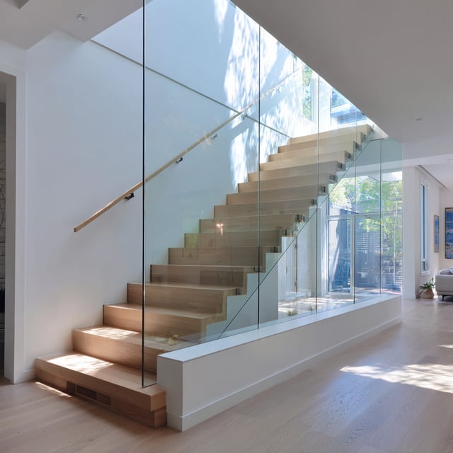 Modern wood staircase enclosed by seamless glass walls.