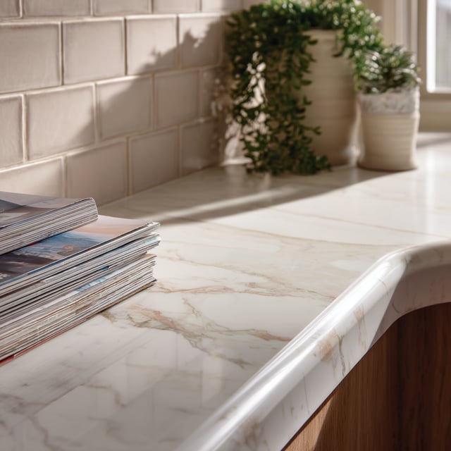 A close-up photograph of a marble countertop with a stack of magazines and potted plants.