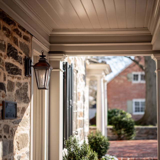  A warm, inviting porch featuring a classic copper lantern and intricate white crown molding.