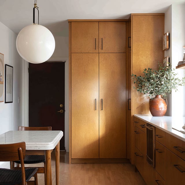 View of a kitchen with tall wood cabinets and a dining area.