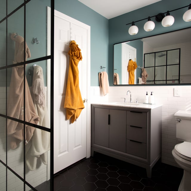 Completed bathroom renovation with large storage vanity and glass shower wall