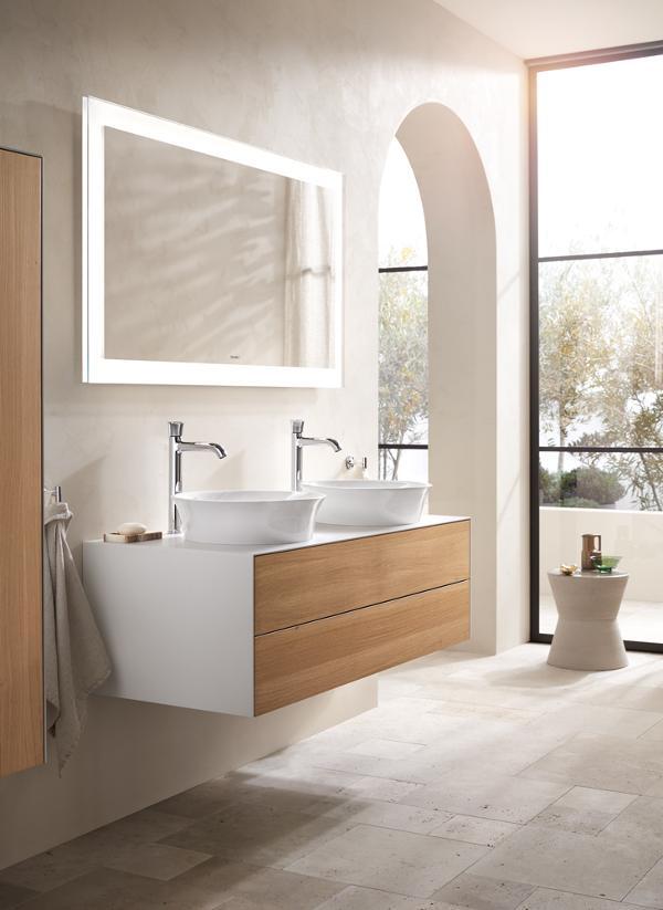 Modern bathroom vanity with double vessel sinks and illuminated mirror.